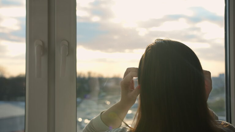 woman looking out the window in the evening, moving camera