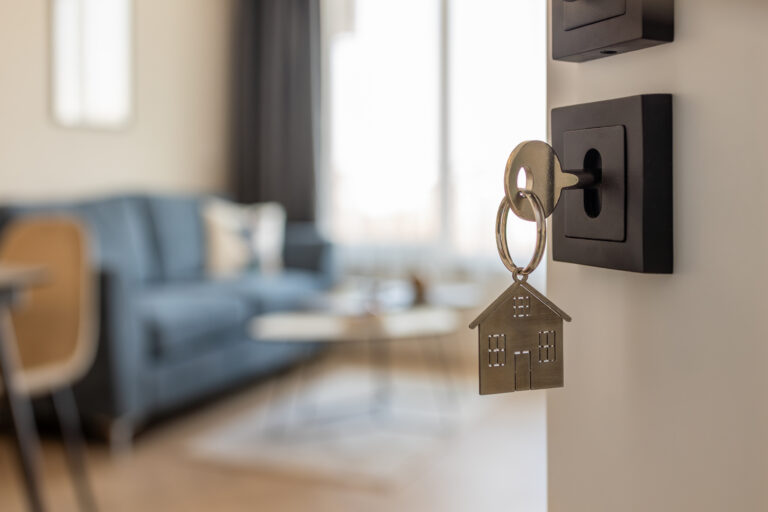 Open door to a new home with key and home shaped keychain